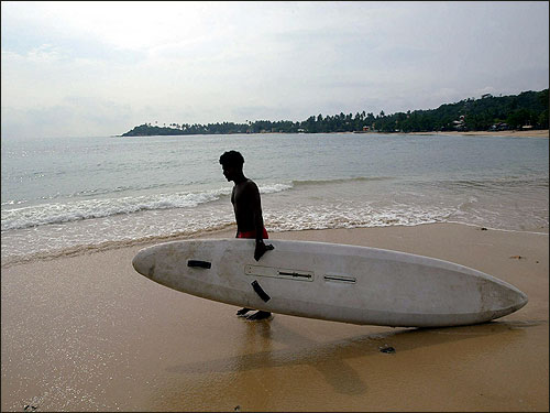 A Sri Lankan man takes his surfboard out to sea in the southwestern town of Galle.