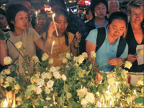 Western tourists and Thais gather on Patong Beach on New Year's to light candles in remembrance of those killed.