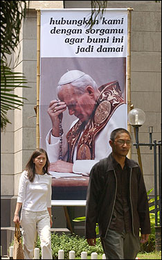 Parishioners pass by a poster of Pope John Paul II outside Jakarta's Main Cathedral in Indonesia on Friday. The sign says in Indonesian, 'Connect us with your heaven to make this world peaceful.'