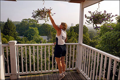 Maura Hennigan watered one of several hanging plants on the third floor deck of her Jamica Plain home.