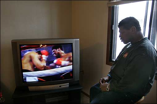 Spinks watches a video of the first Ali-Spinks fight in his apartment in Columbus. Ali used a rope-a-dope strategy in the fight—covering up, staying near the ropes, waiting for Spinks to tire, and then attacking. Spinks never tired and won a split decision.