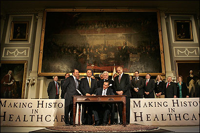 Governor Mitt Romney signed the landmark health insurance bill in Faneuil Hall yesterday as political leaders, including Senator Edward M. Kennedy, looked on.