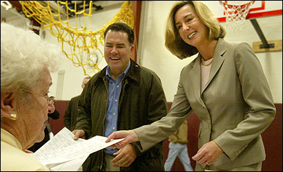 Kerry Healey and husband Sean, get their ballots from Joyce Cressy at the Centerville School in Beverly before voting.