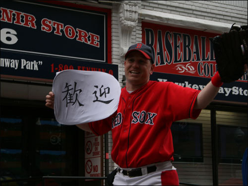 Big League Brian holds up a sign on Yawkey Way that he said that, 'I think it means, 'Welcome.' '
