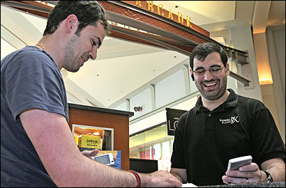 Evan Silbert (right, with customer Raed Nasr) modifies phones in the Shops at the Prudential Center.