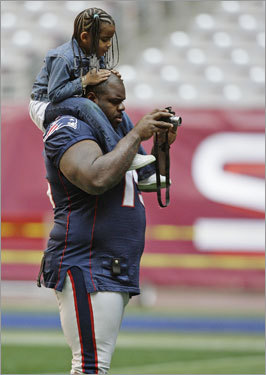 Patriots defensive tackle Vince Wilfork (75) looked at a digital camera with his daughter Destiny on his shoulders.