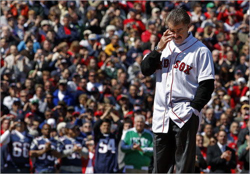 An emotional Bill Buckner wipes his eyes as he is cheered by the crowd, including New England Patriots linebacker Tedy Bruschi (54, backround), and Celtics legend John Havlicek (in green coat next to Bruschi).