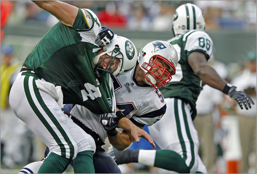 Jets quarterback Brett Favre finds himself wrapped up by Patriots linebacker Tedy Bruschi, but he had some how managed to get off and complete a shovel pass to tight end Chris Baker (86, right).