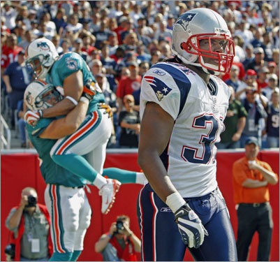 Patriots defensive back Brandon Meriweather (right) heads back to the bench after Dolphins tight end Anthony Fasano (background left) got open and caught a 19-yard touchdown pass from running back Ronnie Brown (not pictured).