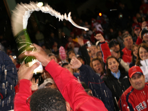 Red Sox coach Ino Guerrero sprays the remaining fans with champagne during the on-field celebration.