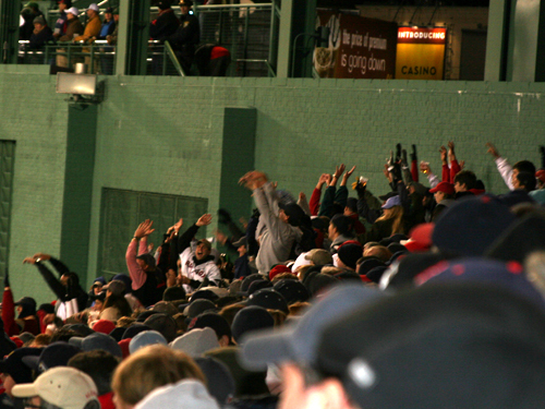 Fans in the bleachers unsuccessfully attempt to get The Wave rolling around Fenway in the seventh inning.