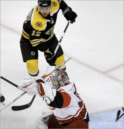 Hurricanes goalie Cam Ward, bottom, makes a save as Boston Bruins right wing Chuck Kobasew (12) looks for a rebound.