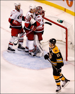 Bruins left wing P.J. Axelsson skates away from a Carolina celebration after the Hurricanes scored a goal.