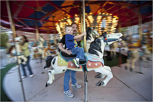 The carousel is the latest in a string of projects to revive the Greenway, among them food trucks, Wi-Fi service, new signs for tourists, patio chairs, and umbrellas. From left, Don Girouard of Grafton and his 3-year-old son Benjamin.