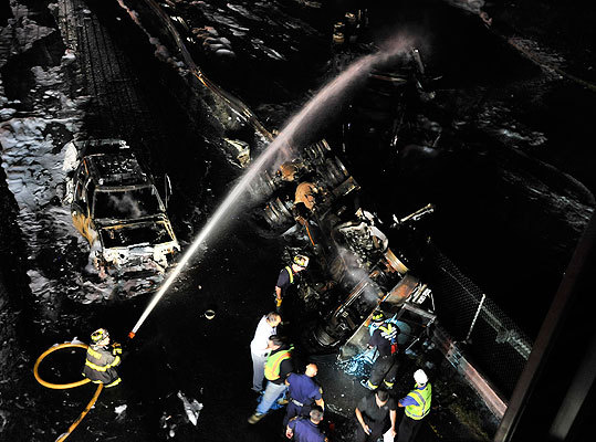 Firefighters hosed down the wreckage of a gasoline tanker that rolled over on Route 1 North in Saugus near the Square One Mall early Saturday Morning, closing the highway, and starting fires as the gas spilled into storm drains into the surrounding neighborhood. (Josh Reynolds for the Boston Globe)