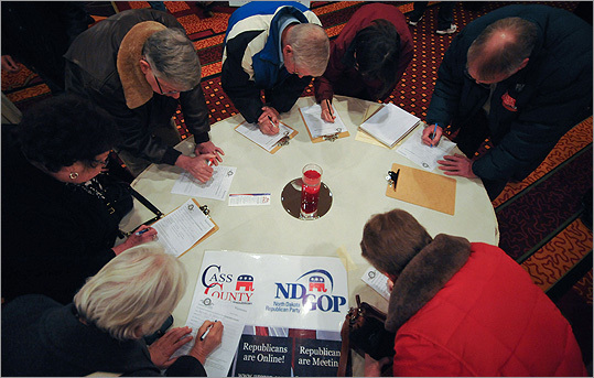 Voters gathered around a table as they filled up registration forms at a caucus site in Fargo, N.D.