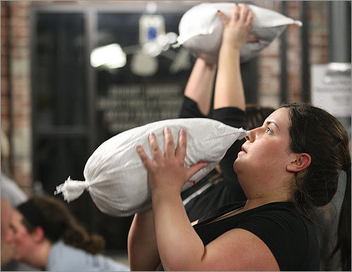 Somerville resident Kristen Callanan, who's a bridesmaid in a wedding July 12, works out with a sandbag. She is one of the first bootcampers at Total Performance Sports, and the only bridesmaid. The rest of the class is filled each week with various club members.