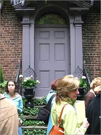 A doorway adorned in ivy and potted white flowers.