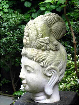 A head of a Thai goddess on a pedestal in the garden.
