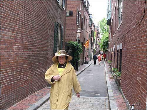 A woman walks down a narrow Beacon Hill street.