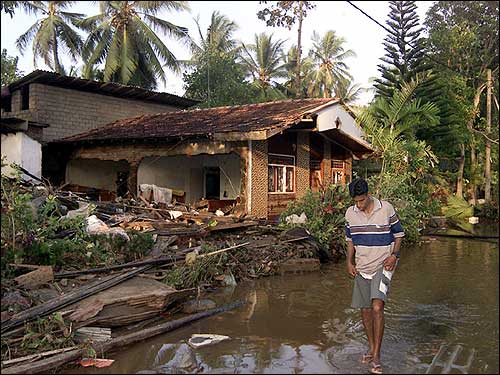 A man walks through what is left of his home.