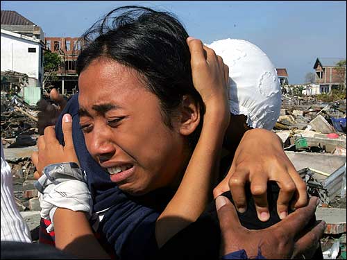 An Acehnese girl cries with her mother near the ruins of their house in Banda Aceh.