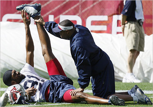 A Patriots trainer helped stretch wide receiver Randy Moss during practice.
