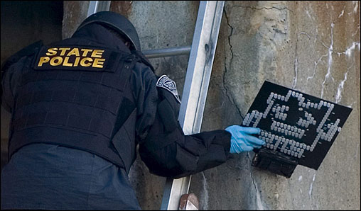 Detectives from the Boston Police Department verify information from the corporation responsible for the advertising campaign. At 4:33 p.m., Turner Broadcasting sends the Globe a statement saying the packages are part of an outdoor marketing campaign for an animated television show. At left, a State Police bomb squad officer removed a device bearing the image of an 'Aqua Teen Hunger Force' character from the McGrath Highway in Somerville.