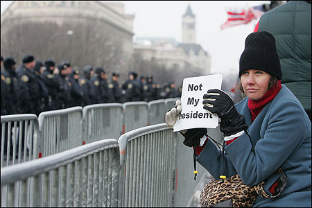 A protester held an anti-Bush sign before President Bush's inaugural parade yesterday. Thousands of law enforcement and military personnel monitored events.