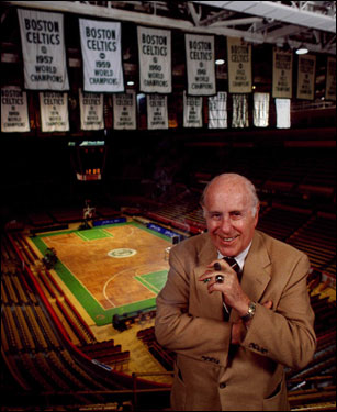 Red Auerbach had a hand in all 16 of the Celtics' championships. Here, he stands in the old Boston Garden, a cigar in his hand and the banners hanging in the background.