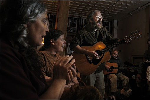 Some of the Plymouth members sing and play music to celebrate the Sabbath; John (Malachi) Howley (standing) plays guitar.