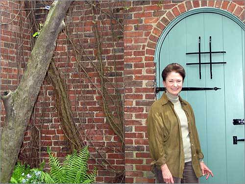 Lynda Shubert Bodman poses in front of a garden gate.