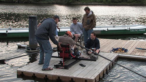 This unusual group of rowers and researchers met on a Charles River dock throughout the spring. On this occasion, Estrada uses electrodes on his legs while simulating full-body rowing on an anchored raft. Tom Darling, a three-time Olympic rower, gives Estrada a helpful push. Darling had been prodding the researchers and paraplegics to take their rowing exercise from the Spaulding lab to the Charles River for months.