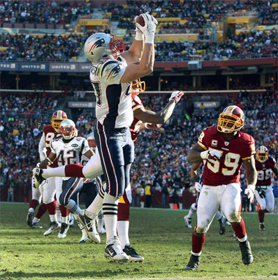 Patriots tight end Rob Gronkowski with this catch, his first touchdown of the game, set the NFL record for most touchdown passses caught by a tight end in a season. Washington's safety DeJon Gomes (24), couldn't stop him, as Redskins LB London Fletcher (59) looked on at right. After the game, 'Gronk' said <a href='http://www.boston.com/sports/football/patriots/extra_points/2011/12/rob_gronkowski_4.html '>it was all about winning .