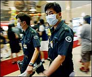 A sanitary inspector directs migrant workers to check their temperatures before they board trains at a railway station in Beijing on May 28.