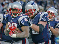 Corey Dillon (left) cradles the ball after he scored the game winning touchdown, as teammates Matt Light (72) and Heath Evans (far right) join the party.