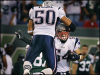 Tedy Bruschi smiles as he clutches the ball he just intercepted as fellow linebacker Mike Vrabel (50, left) leaps into his arms in celebration of the game-ending play. 