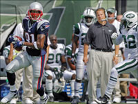 Patriots wide receiver Randy Moss (81) gives Jets head coach Eric Mangini (background right) a good look as he picks up a first down just before the two minute warning in the first half with 33 of his 183 yards receiving on the afternoon on this pass from Tom Brady.