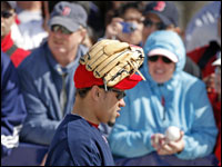 It was pretty cold in Fort Myers today (which explains the clothing on the fans in the backround) so maybe Red Sox pitcher Manny Delcarmen was trying to keep his head warm with his glove as he left the field.  (Globe Staff Photo/ Jim Davis)
