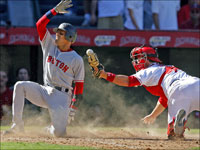   Red Sox SS Julio Lugo slides in with the first of the seven Boston runs in the eighth innning of Game 3 of the ALDS, scoring on a Dustin Pedroia double and knocking the ball out of Angels catcher Mike Napoli's mitt at the same time. (Jim Davis/Globe Staff)