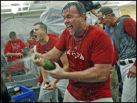 Sean Casey sprays champagne in the Red Sox clubhouse, with Jonathan Papelbon howling in the backround at left. (Jim Davis/Globe Staff)