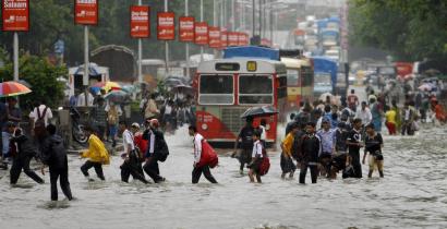 Flooding in Mumbai forced people yesterday to wade through knee-deep water that covered many streets after severe overnight rains overwhelmed sewers.