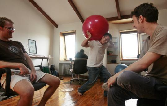 Daniel Choi, a Web applications engineer for Notati, struck an Atlas pose last month for Nate Aune (left), founder of Jazkarta, and Dave Fisher at Betahouse, a communal workspace in Cambridge.
