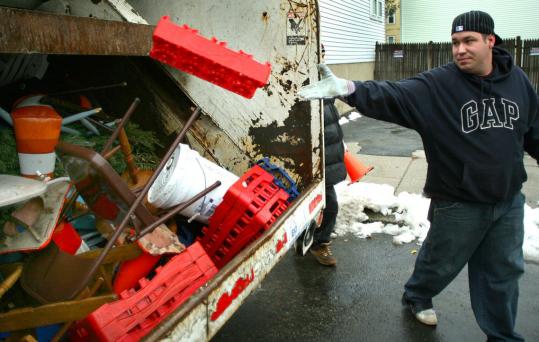 Public Works employee Alex Cappellano flung a bottle container into his truck on D Street in South Boston yesterday during a sweep of items 'reserving' snow-cleared parking spaces.