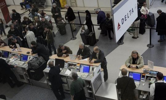Passengers wait to check in at the Delta Air Lines ticket counter at O'Hare International Airport in Chicago yesterday, when American Airlines and Delta canceled hundreds of flights.