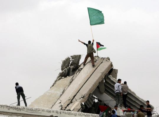 On the 60th anniversary of Israel's creation, a Palestinian youth held a Hamas flag as he climbed ruins in Gaza Strip.