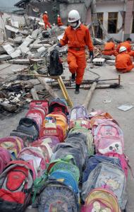 A rescuer collected backpacks from a collapsed school in Shifang, located in Sichuan Province in southwest China. Officials say more than 50,000 people probably died in the earthquake.