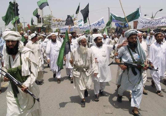 Supporters of Jamat Ahl-e-Sunnat, a Pakistani Islamic group, guarded colleagues during a protest yesterday against the country's president and an alleged US missile attack in Pakistan's tribal area.