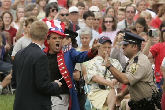 A protester was led away yesterday during President Bush's speech at a naturalization ceremony in Charlottesville, Va.
