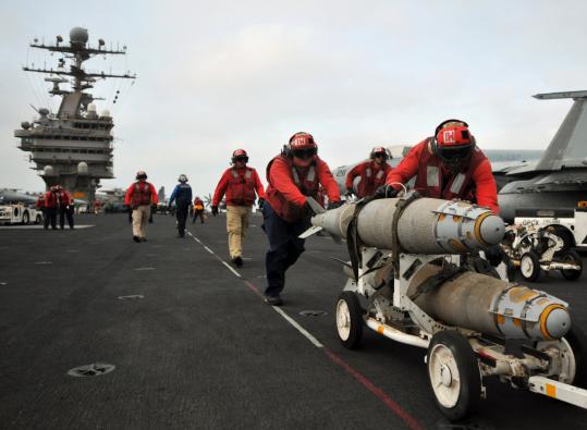 Bombs were pushed into position to be loaded onto aircraft yesterday aboard the USS Abraham Lincoln. The carrier was moved out of the Persian Gulf and to the Gulf of Oman.